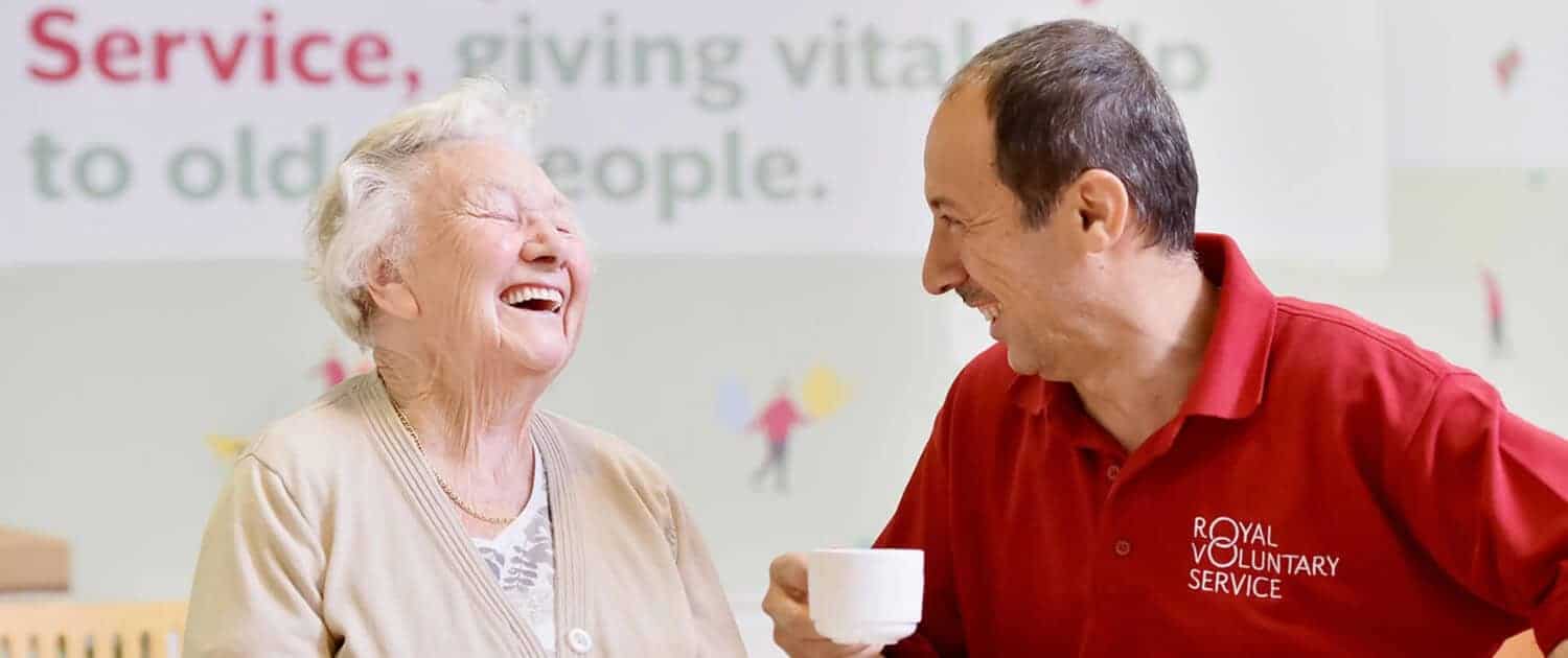 royal voluntary service image of volunteer and service user laughing and smiling.