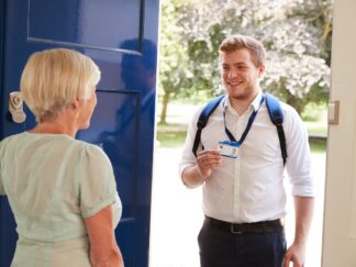 A woman answering a door to a man wearing a back pack, showing his badge. Home Care vs Care Homes