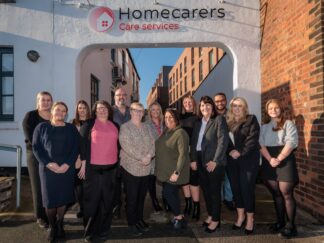 Image of a group of people in an office setting, wearing a care assistant uniform.