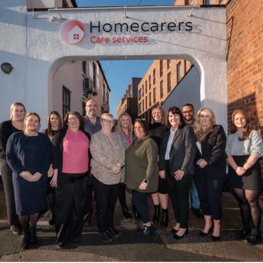 A group of people stood in front of a building with a plaque stating 'Homecarers Care Services'