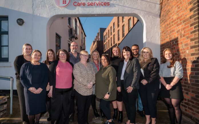 Image of a group of people in an office setting, wearing a care assistant uniform.