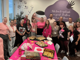 Image of a group of people wearing pink, behind a pink table full of buffet food.