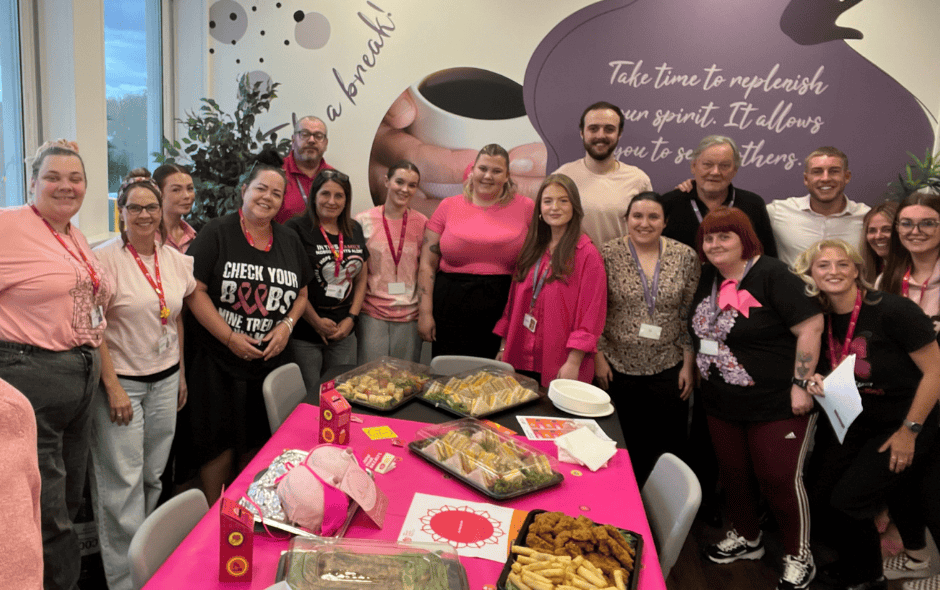 Image of a group of people wearing pink, behind a pink table full of buffet food.