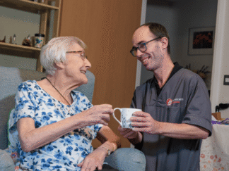 An image of a Care Assistant and an elderly lady, bonding over a cup if tea.