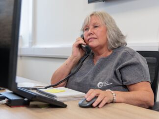 An image of a woman sat at a desk answering a phone call.