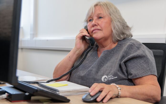 An image of a woman sat at a desk answering a phone call.