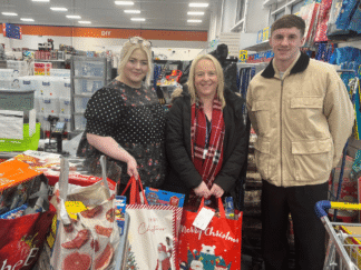Image of 3 people with bags of toys in a large supermarket.