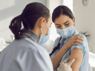 Image of a nurse giving a patient a flu jab in a hospital setting.