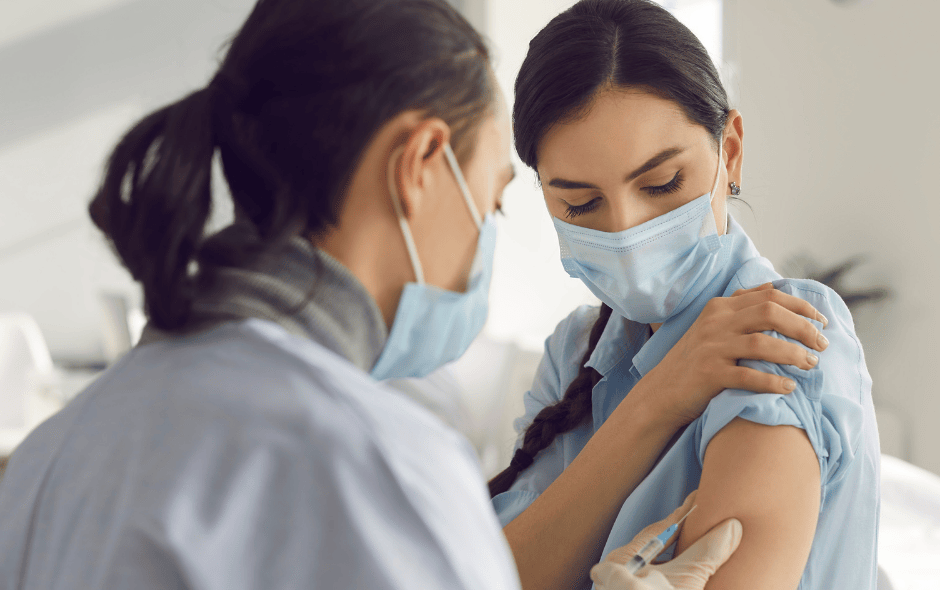 Image of a nurse giving a patient a flu jab in a hospital setting.