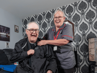 Image of two people in a home, smiling and laughing.
