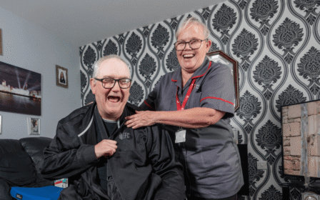 Image of two people in a home, smiling and laughing.