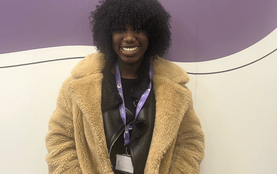 image of a woman stood in front of a mural, wearing a large fur coat.