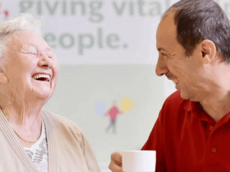 An image of 2 people laughing over a cup of tea.