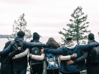 Image of 5 people hugging in a snowy forest.