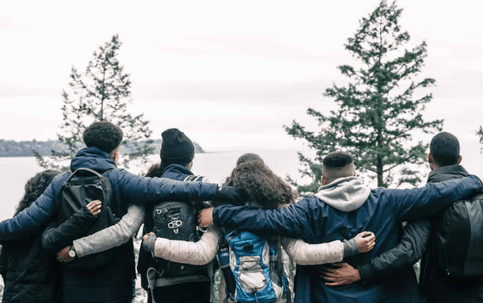 Image of 5 people hugging in a snowy forest.