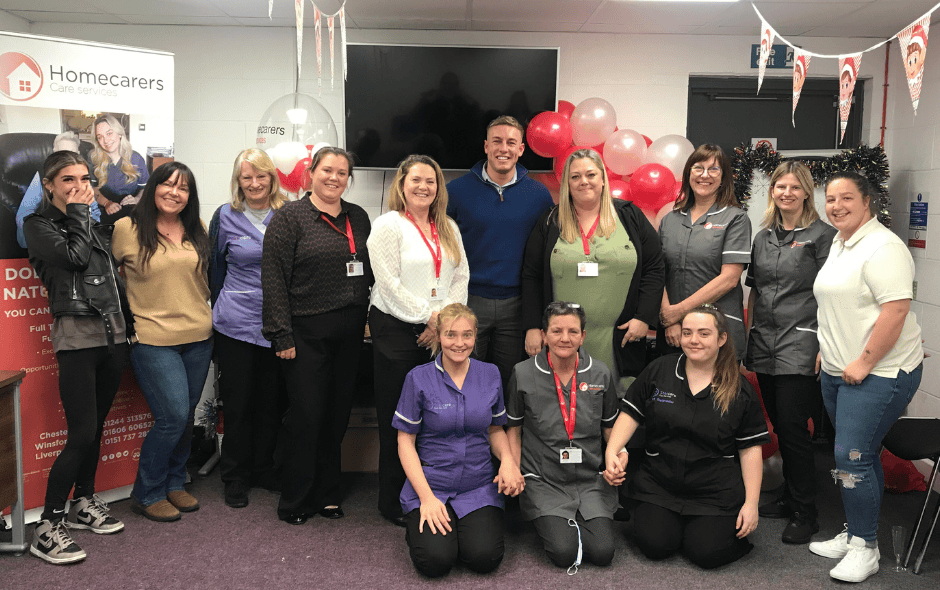 Image of a room full of colleagues, taking part in celebrations with red balloons and red bunting in the background.