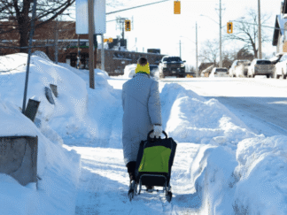 Image of an elderly person walking through snowy conditions.