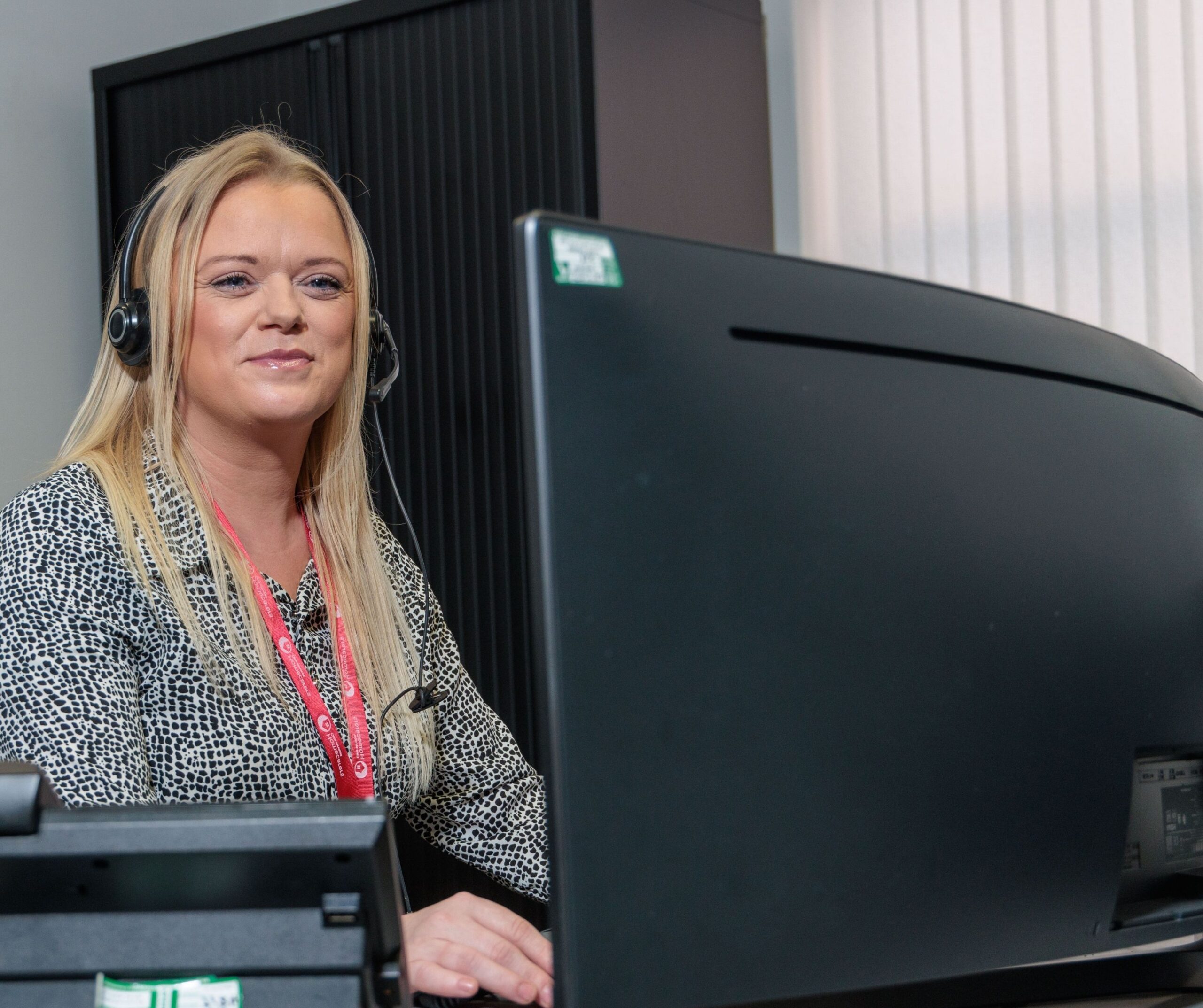 An image of a woman sat at a desk with a headset on.