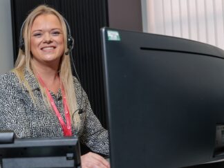 An image of a woman sat at a desk with a headset on, typing on her keyboard. getting started