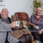 Image of a service user and a Care Assistant, smiling and laughing whilst holding a cup of tea.