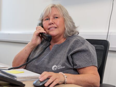 An image of a woman sat at a desk answering a phone call.