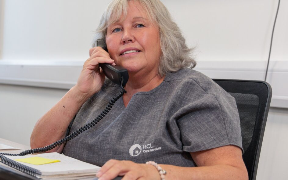 An image of a woman sat at a desk answering a phone call.