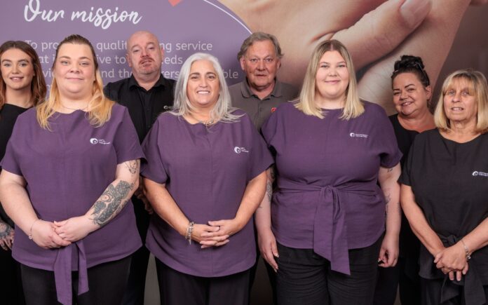 Image of a group of people in an office setting, wearing a care assistant uniform.