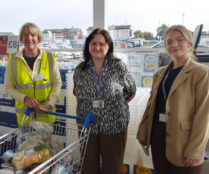 3 individuals taking part in a foodbank donation at a Tesco Superstore